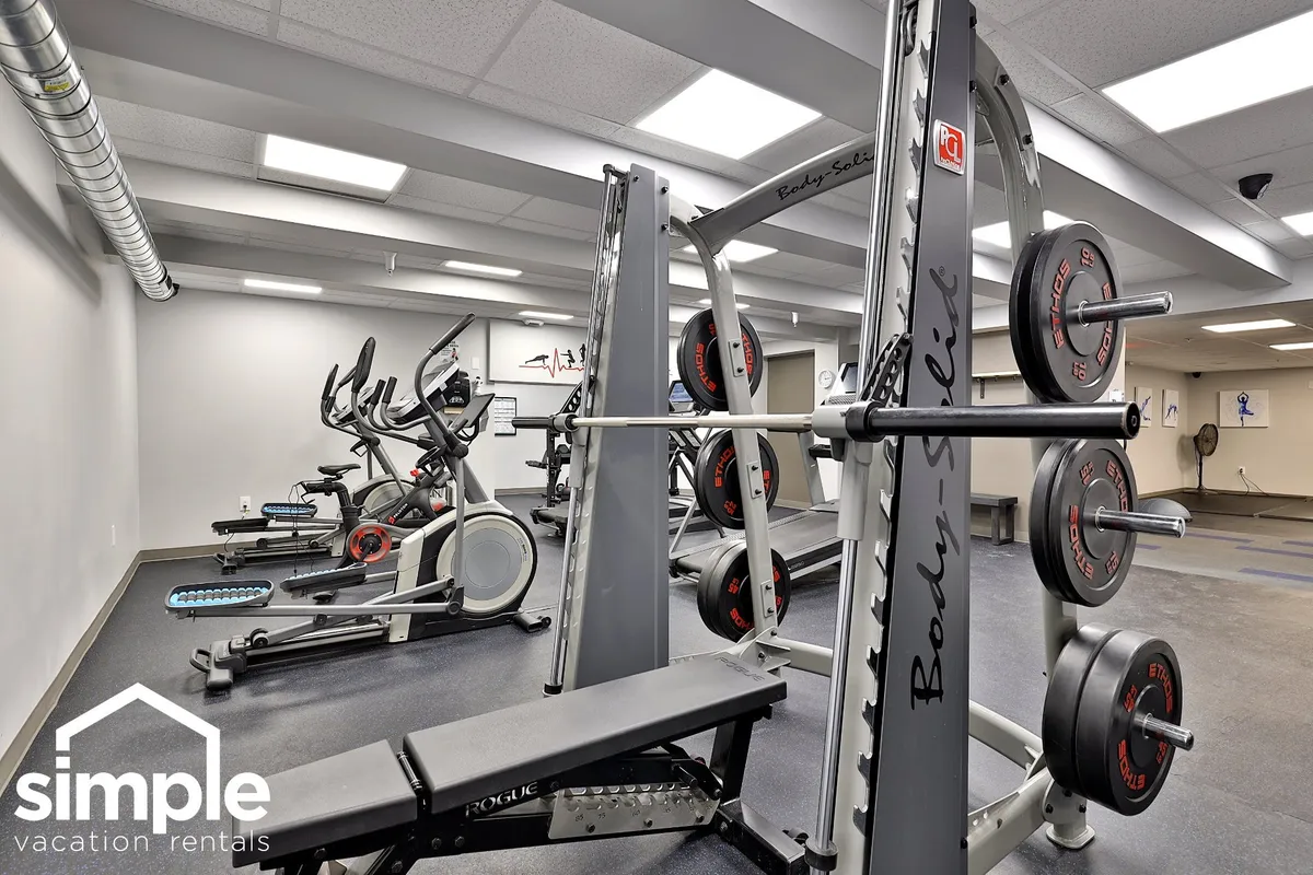A well-equipped fitness center filled with cardio machines, weightlifting equipment, and exercise mats. The space is energetic and designed for a range of workouts, offering a glimpse of the active amenities available onsite.