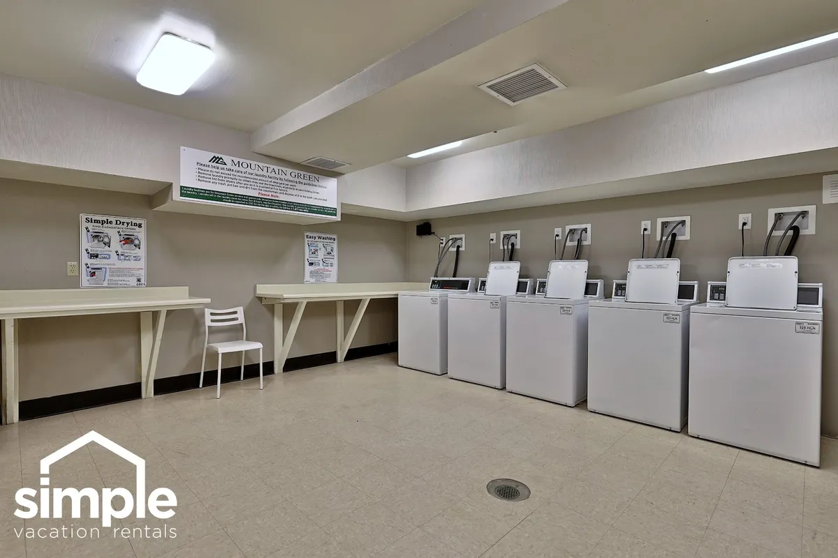 A functional and tidy community laundry facility with washing machines, a drying area, and informational posters, highlighting the convenience of on-site laundry for guests.