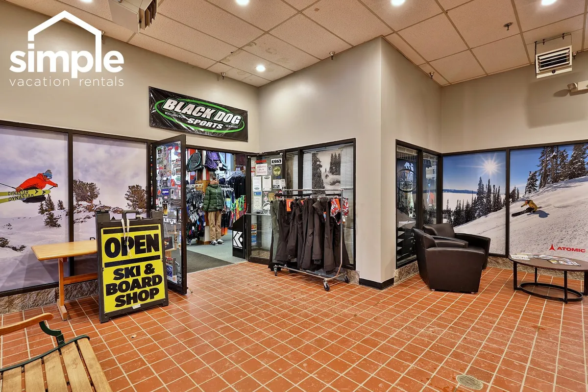 An interior scene of the Black Dog Sports shop, displaying ski and snowboard apparel, with an inviting open sign and a sense of bustling preparation for outdoor activity.